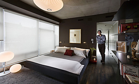 In this photograph, Chicago artist Lincoln Schatz stands in the doorway of the master bedroom with a charcoal gray bed and Chinese red side table. (Bill Hogan/Chicago Tribune/MCT)